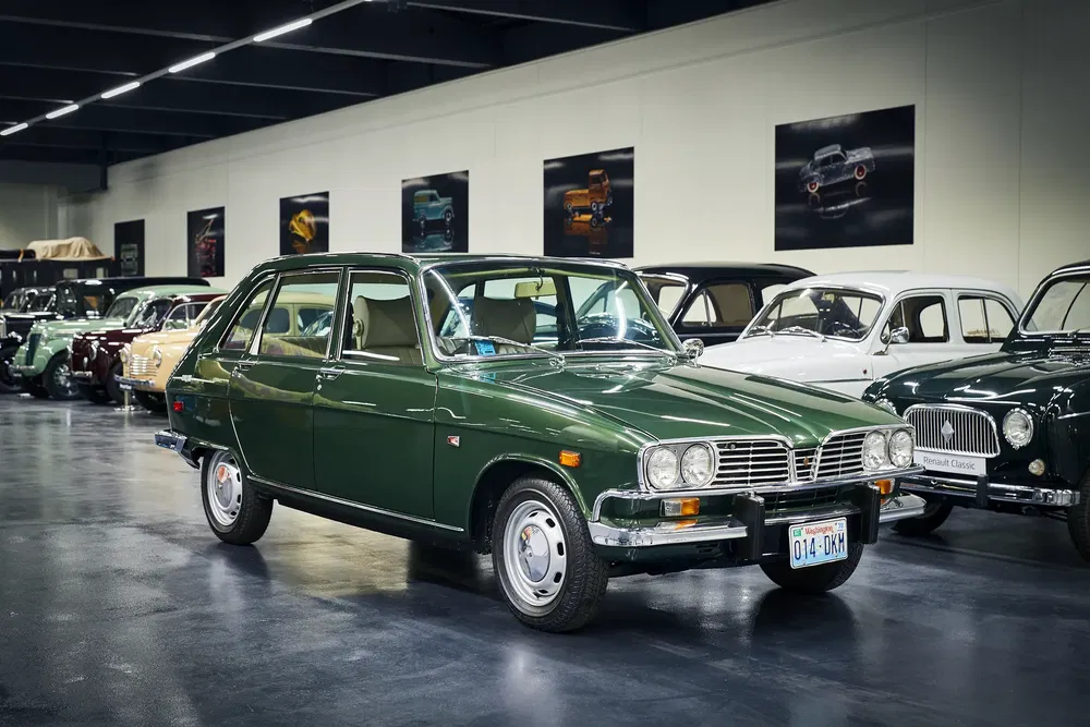 Voiture rétro R11 verte exposée dans un musée automobile avec voitures classiques en arrière-plan.