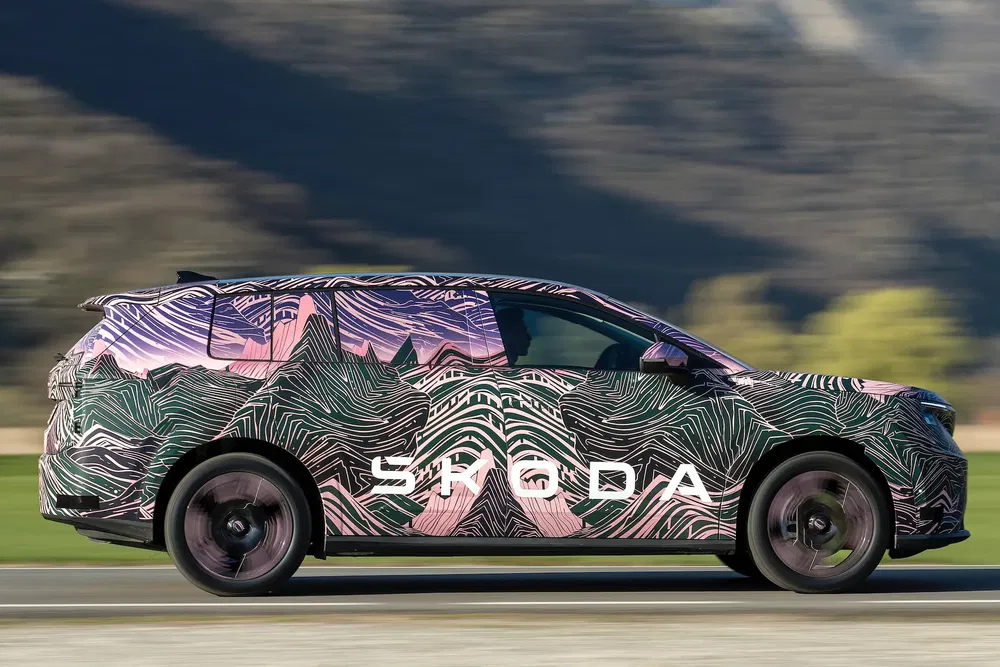 Škoda-auto met kleurrijk camouflagepatroon, rijdend in landelijke omgeving.