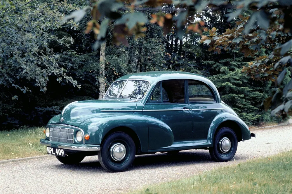 {"fr":"Morris Minor vert classique stationné dans un cadre boisé.","nl":"Klassieke groene Morris Minor geparkeerd in een bosrijke omgeving."}