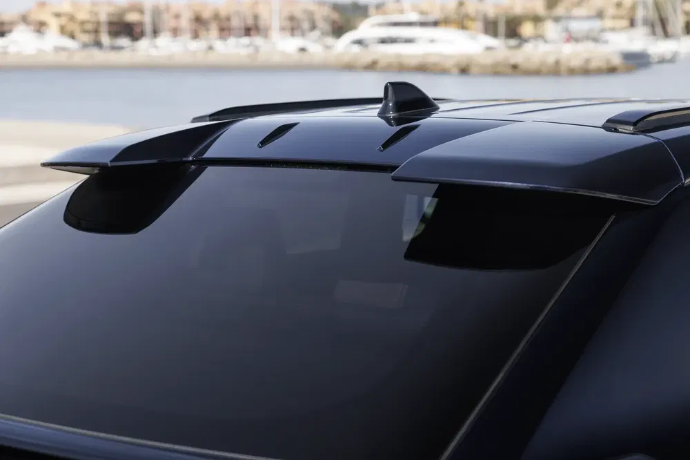 Moderne auto dakspoiler met haaienvinantenne, havenachtergrond.