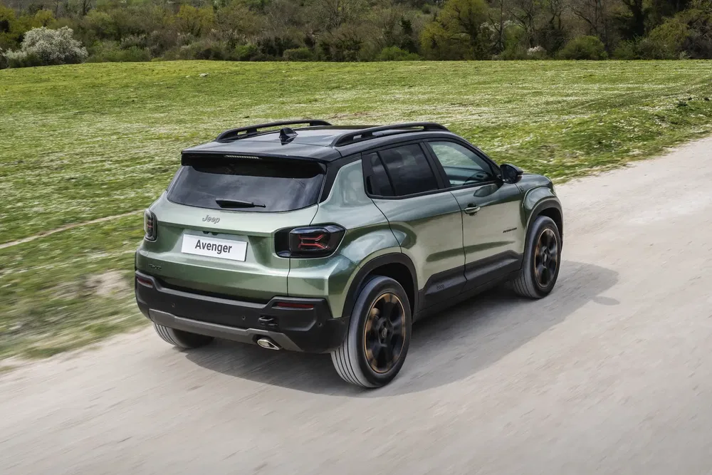 Jeep Avenger vert roulant sur une route de campagne ensoleillée.