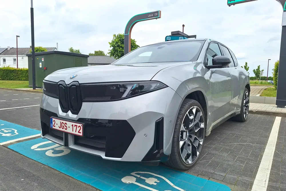 {"fr":"BMW iX grise stationnée sur une aire de recharge électrique, design moderne et élégant.","nl":"Grijze BMW iX geparkeerd bij een elektrische laadplek, modern en elegant ontwerp."}
