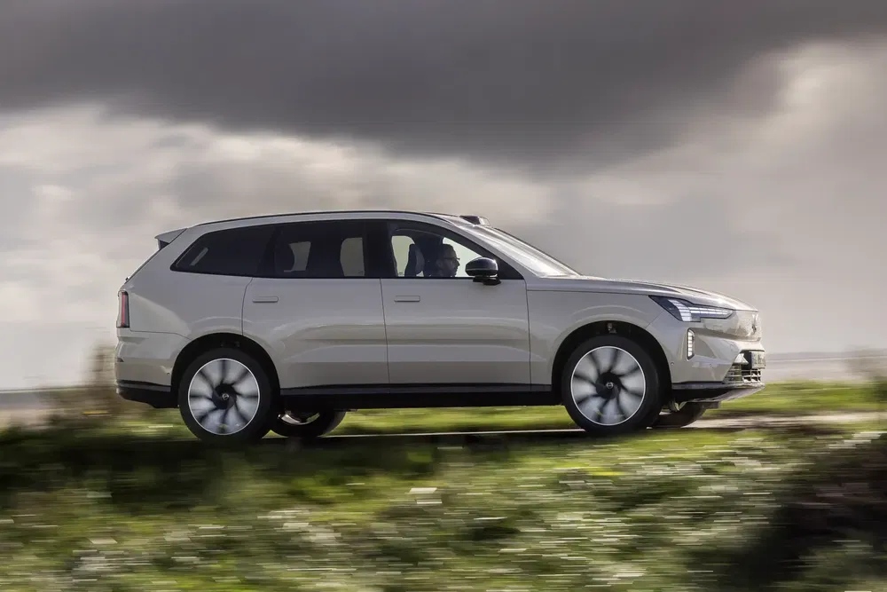 SUV électrique Volvo EX90 roulant sur route sous ciel nuageux.