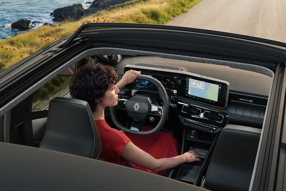 Rijden in een Renault met modern dashboard langs een schilderachtige kustweg.