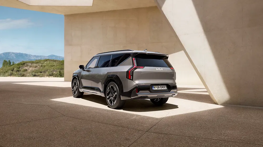 SUV Kia argenté dans un cadre architectural moderne sous la lumière du soleil.