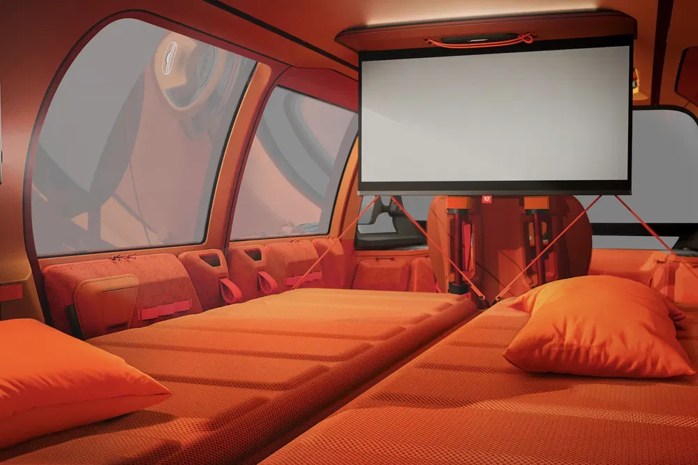 Intérieur de voiture Subaru aménagé en espace de couchage avec écran de projection.