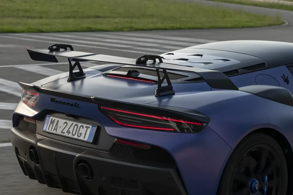 Maserati MC20 bleu avec aileron sur circuit, arrière élégant et sportif.