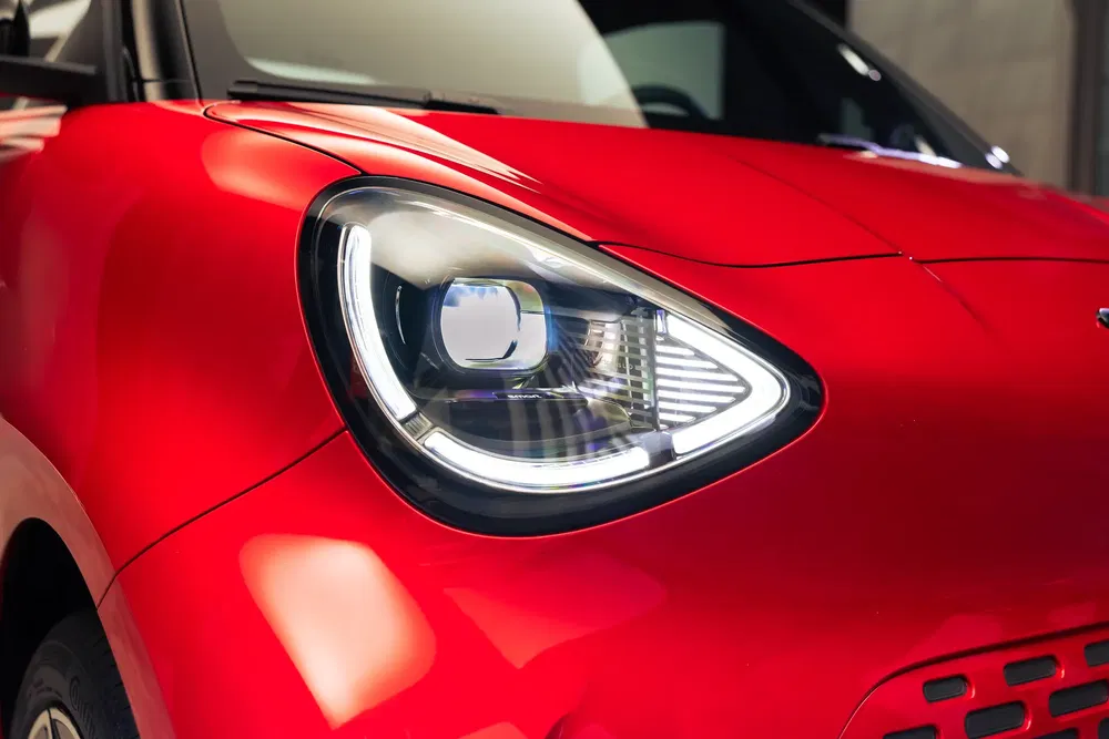 Close-up van een moderne rode elektrische auto koplamp, gestroomlijnd aerodynamisch ontwerp.