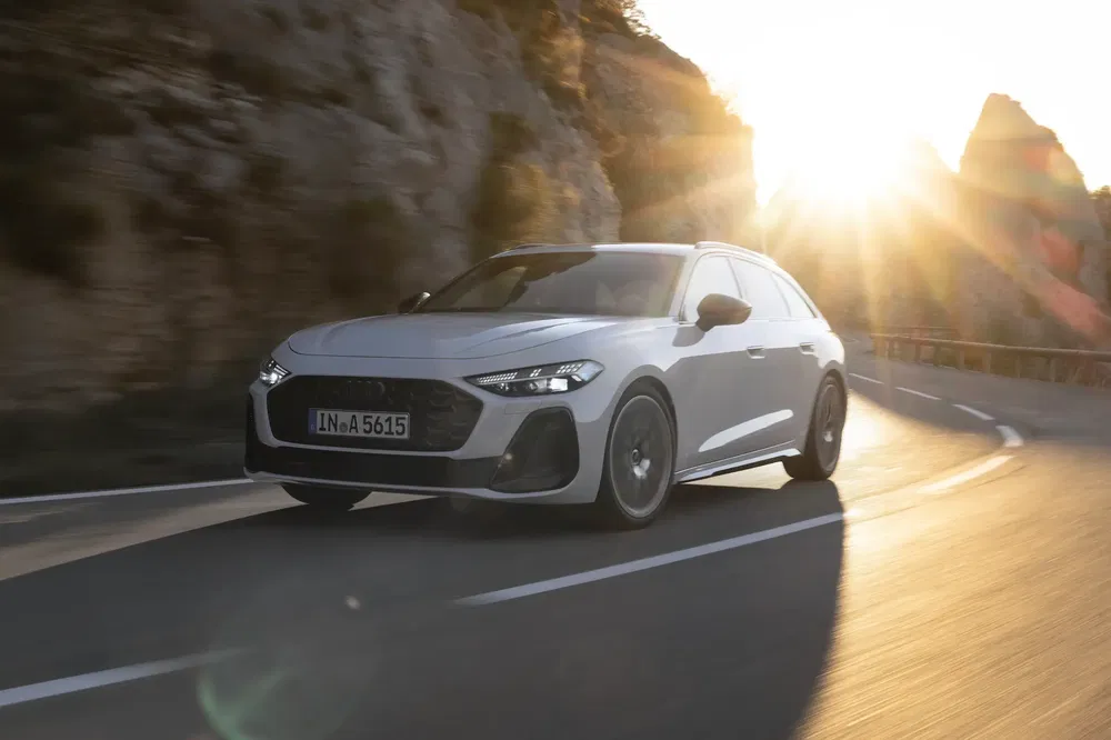 Audi A6 2024 blanche sur route sinueuse au coucher du soleil.