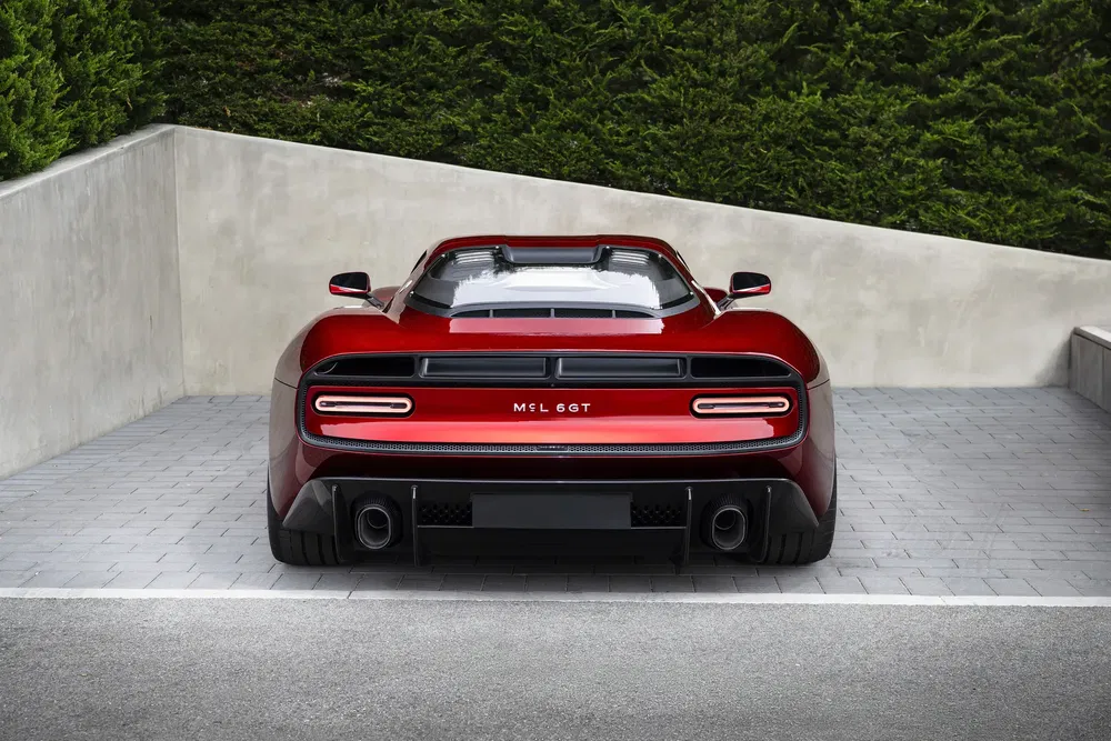 Achteraanzicht van de rode Mazzanti Evantra Millecavalli op een geplaveide oprit.
