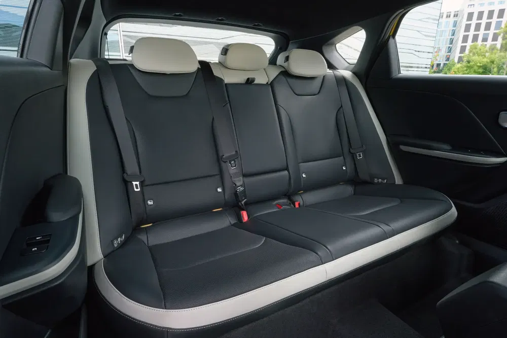 Intérieur de voiture moderne avec sièges arrière en cuir noir et écrans-tactiles intégrés.