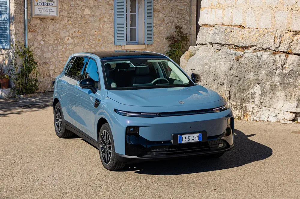 Véhicule électrique Zeekr X bleu garé devant un bâtiment en pierre, style moderne et urbain.