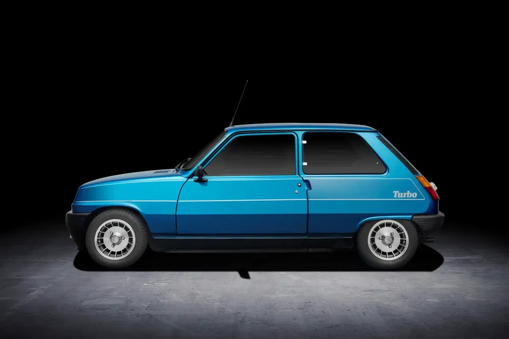 Renault 5 Turbo bleue profil gauche, fond noir, jantes emblématiques, emblème Turbo visible.