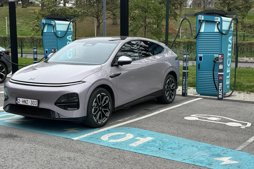 Voiture électrique moderne en charge à une station Electra, design futuriste et aérodynamique.