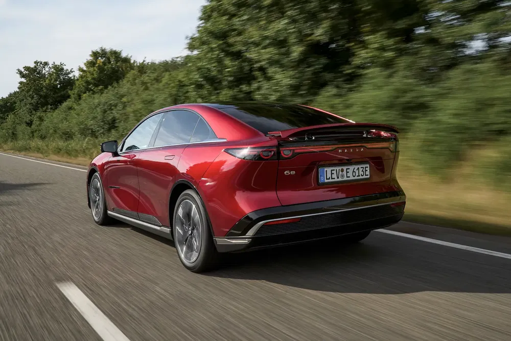 {"fr":"Mazda rouge électrique, arrière, sur une route, avec paysage verdoyant en arrière-plan.","nl":"Rode elektrische Mazda, achterkant, op een weg, met groen landschap op de achtergrond."}