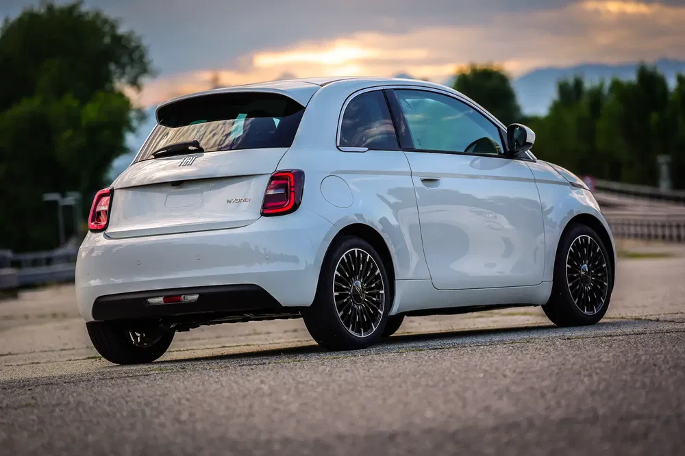 Fiat 500 blanc sur route au coucher du soleil, design compact et moderne.