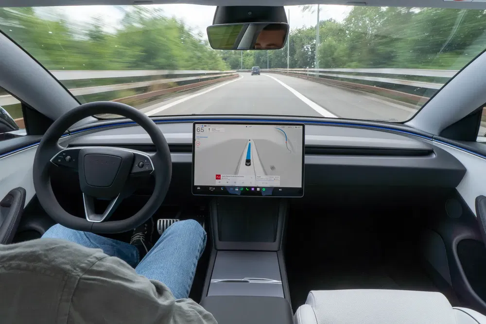 {"fr":"Intérieur d'une voiture autonome avec écran de navigation, volant et passager avant sur route.","nl":"Interieur van zelfrijdende auto met navigatiescherm, stuur en passagier op de snelweg."}
