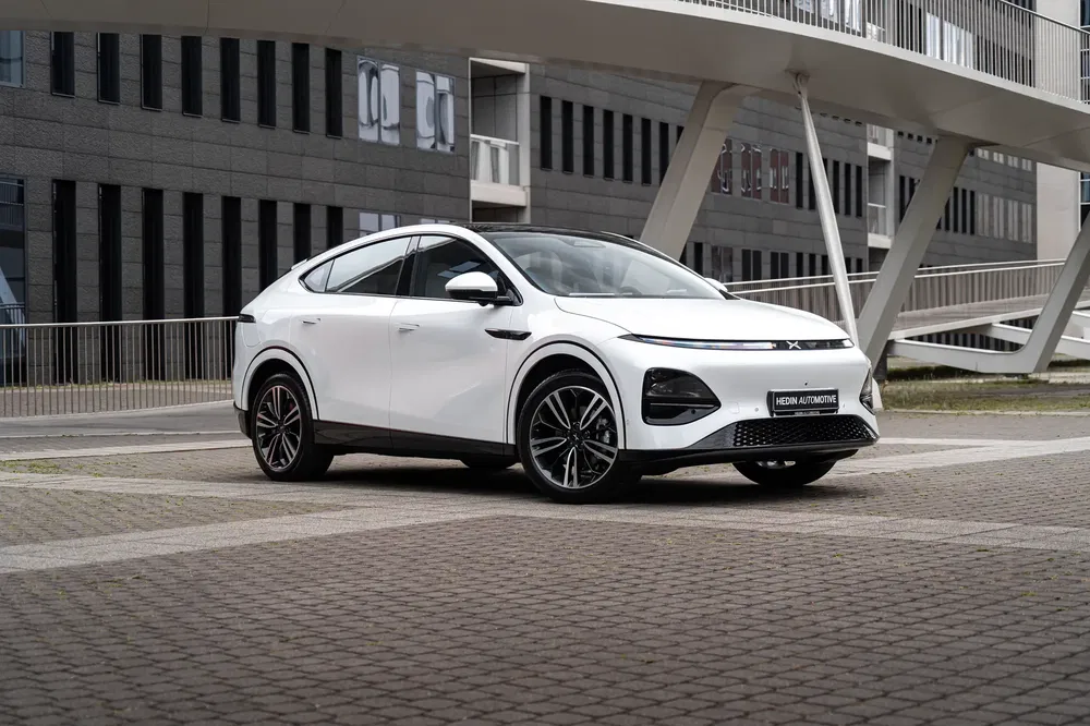 SUV XPeng blanc garé devant un immeuble moderne, design élégant et futuriste.