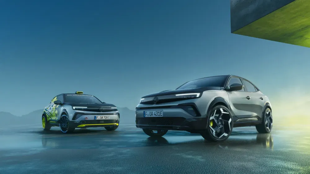 Deux Opel Mokka électriques en stationnement sur une surface métallique sous un ciel nuageux.