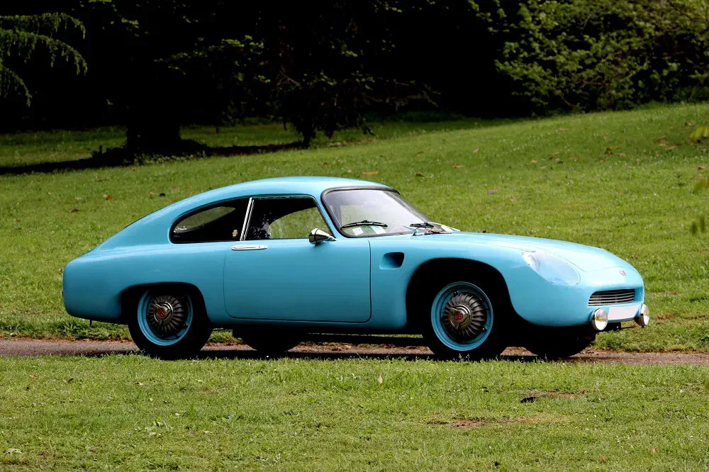 Classic car bleu turquoise sur pelouse verte, design aérodynamique rétro années 60.