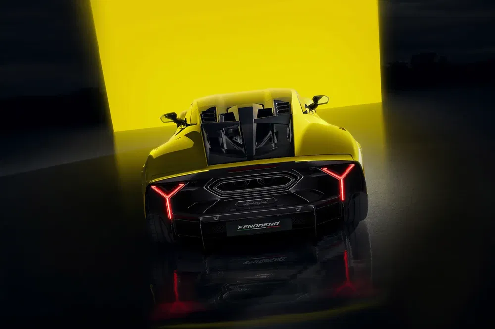 Supercar Lamborghini Revuelto jaune, éclairage arrière distinctif, posé devant un fond lumineux.