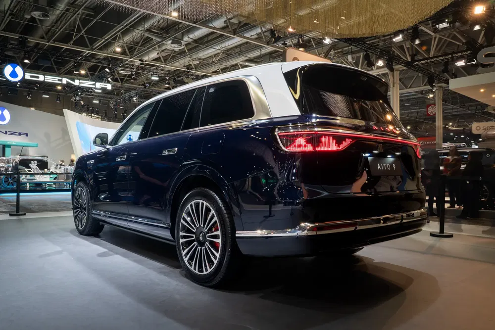 SUV Aito 9 bleu en exposition au salon de l'automobile, éclairage de stand moderne.