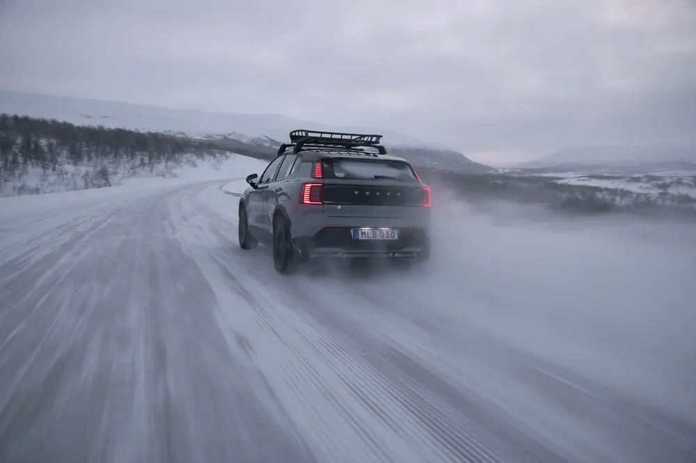 Volvo XC90 roulant sur route enneigée, conditions hivernales extrêmes, paysage montagneux en arrière-plan.