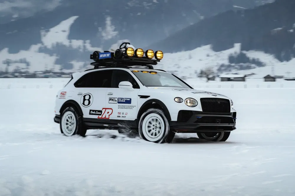 Witte Bentley Bentayga op sneeuw met daklampen en rallystickers.