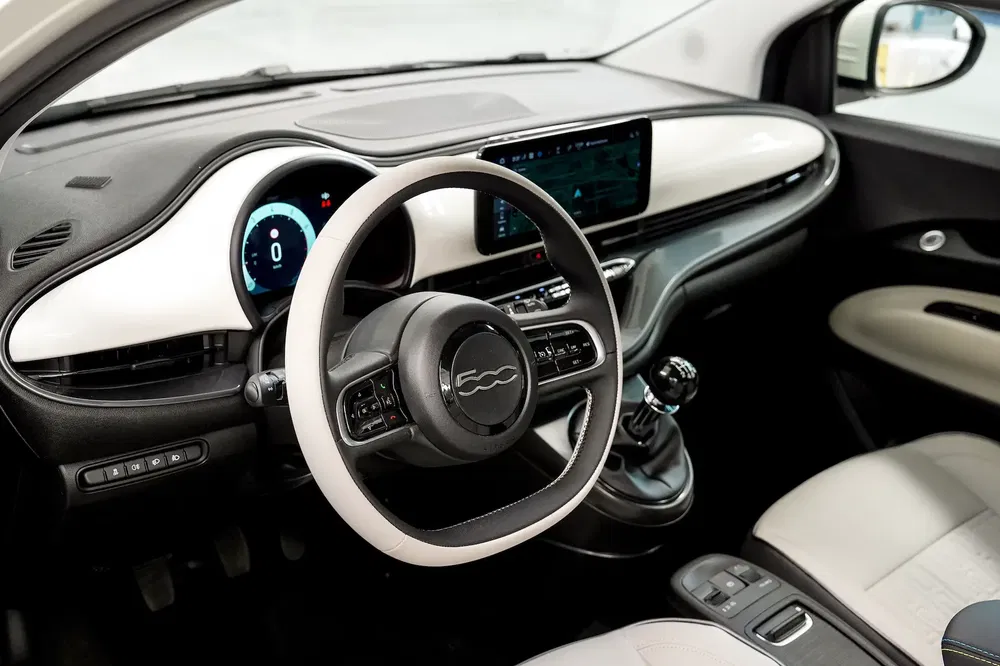 Intérieur moderne de la Fiat 500 avec volant et tableau de bord numériques élégants.