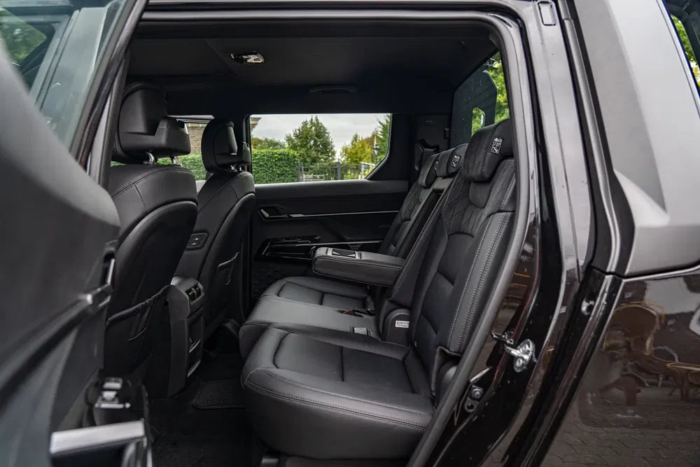 Intérieur spacieux du SUV Mazda CX-90 avec sièges en cuir noir et accoudoir central.