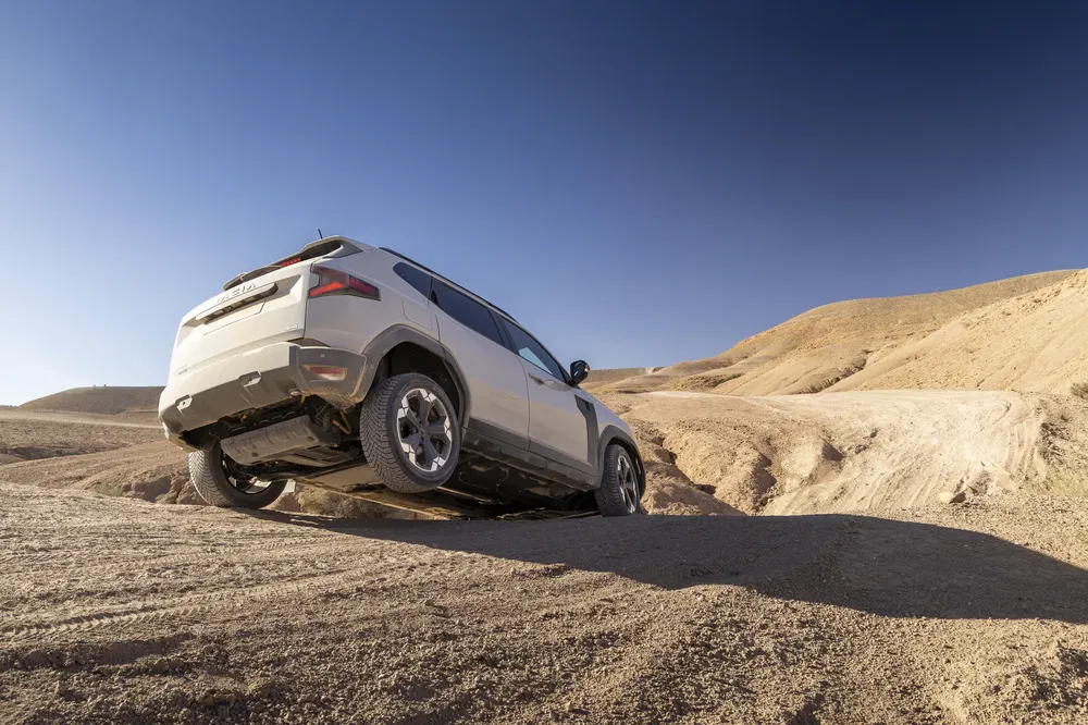 Witte SUV off-road in een woestijnlandschap met heldere blauwe lucht.