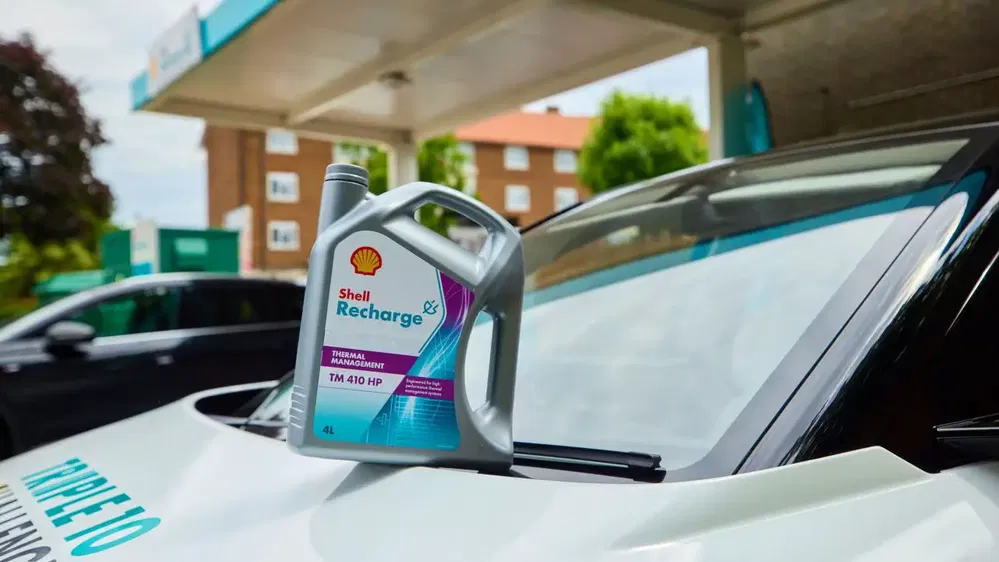 Bidon d’huile Shell Recharge TM 410 HP posé sur le pare-brise d'une voiture.