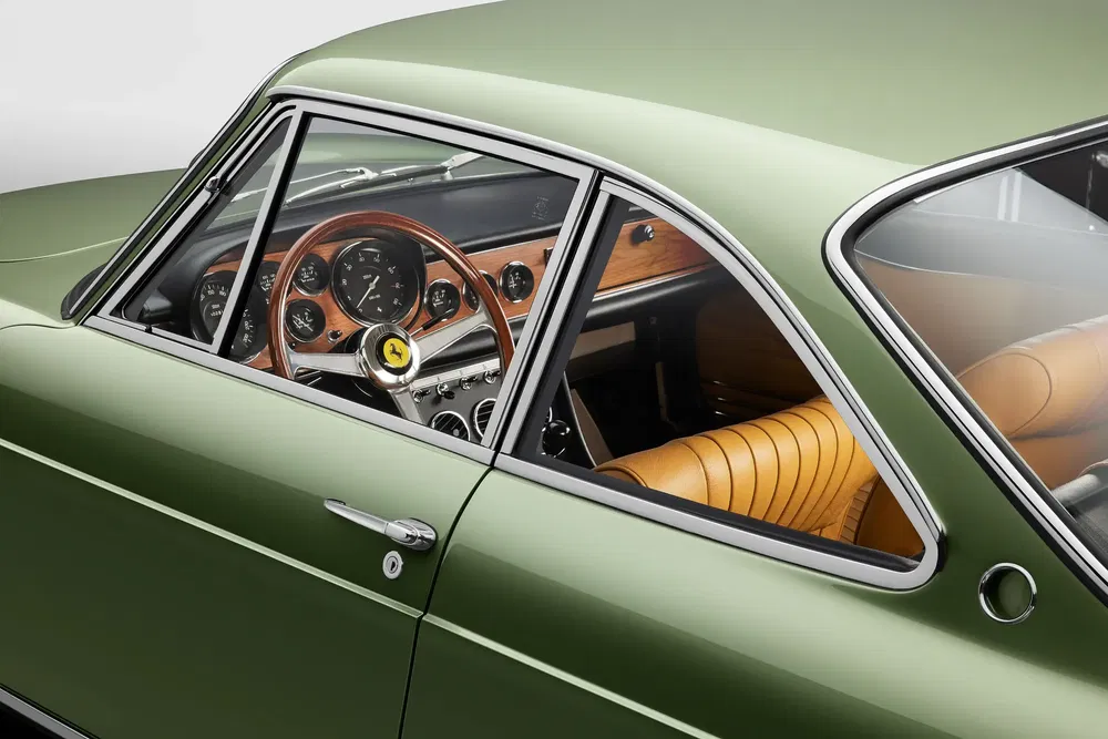 Intérieur classique d'une Ferrari avec volant en bois et sièges cuir marron.
