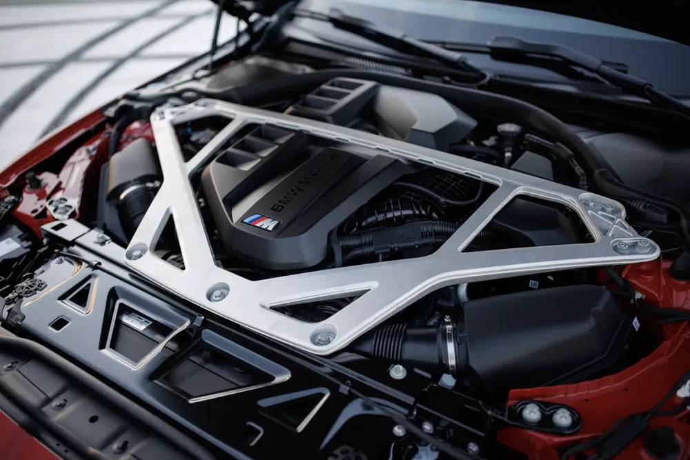 BMW M motor onder geopende motorkap, krachtig ontwerp en iconisch logo zichtbaar.