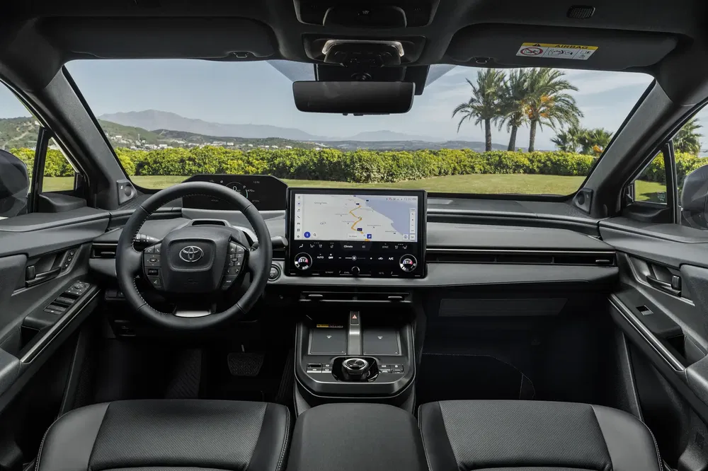 Interieur van de Toyota bZ4X met modern digitaal dashboard en groene buitenzicht.