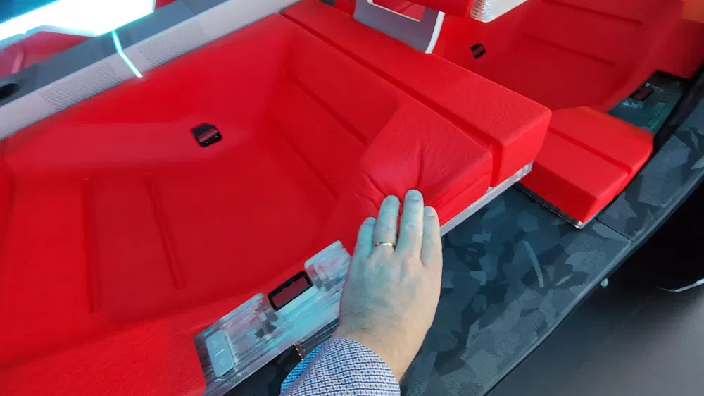 Intérieur futuriste de voiture avec sièges rouges, montré avec une main touchant le tissu.
