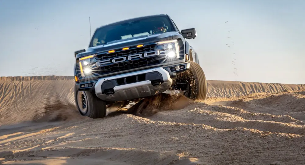 Ford F-150 traversant des dunes de sable à grande vitesse dans un désert ensoleillé.