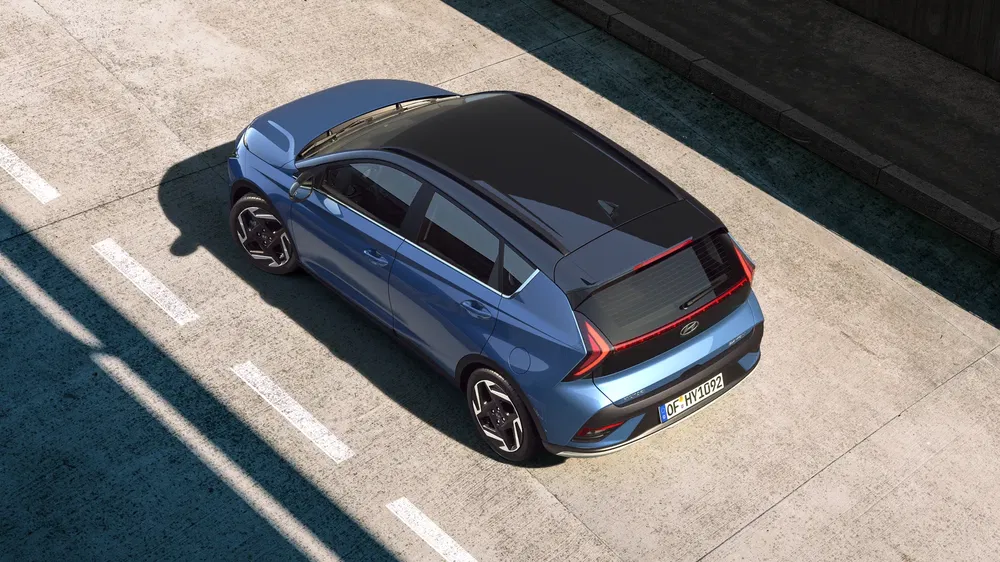 Vue aérienne d'une Hyundai i30, couleur bleue, sur une route en béton, lumière solaire.