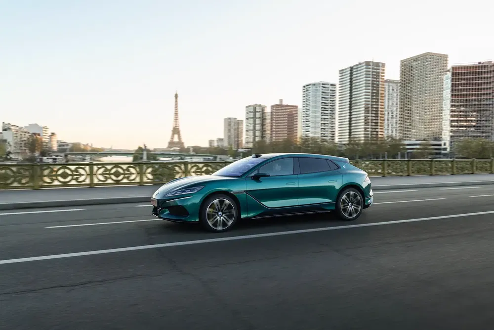 Voiture électrique MG MG5 roulant à Paris avec la tour Eiffel en arrière-plan.