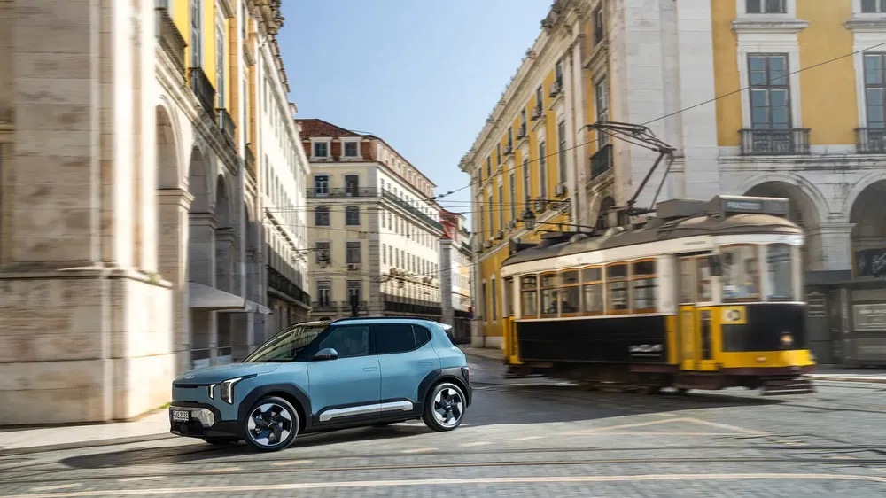 SUV Kia électrique devant tramway historique dans rue pavée de Lisbonne.