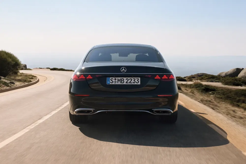 Mercedes-Benz S-Klasse rijdt op een schilderachtige weg, elegante en moderne achterkant.