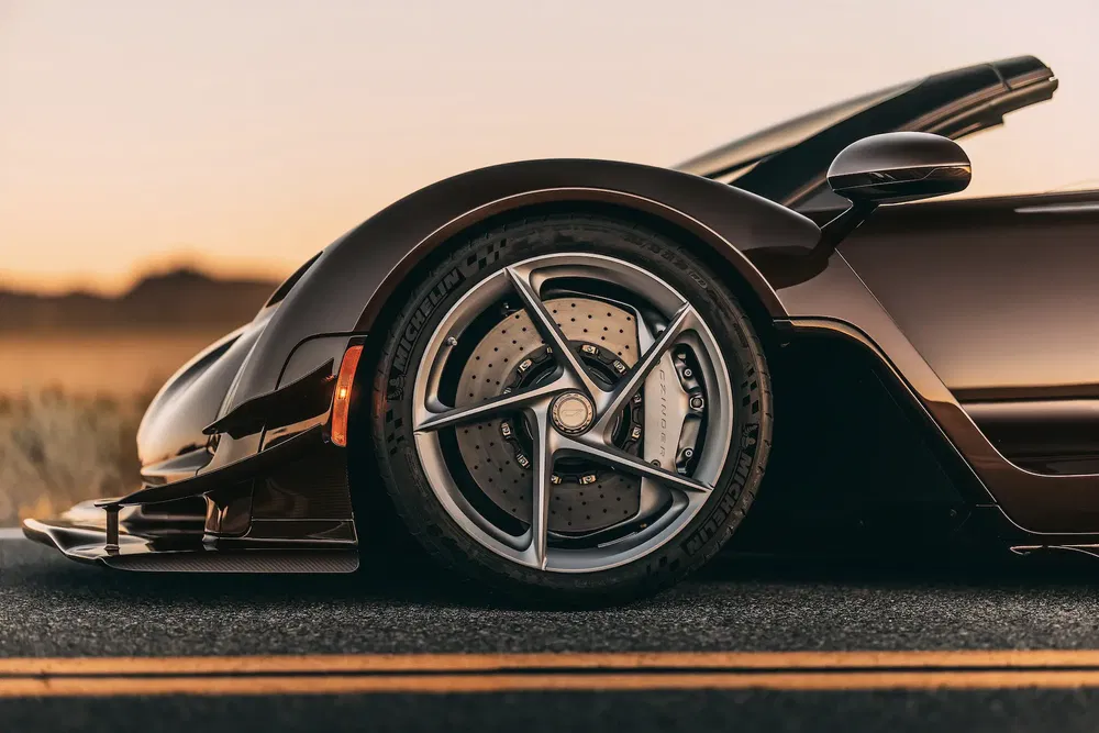 Roues avant en gros plan d'une supercar noir, Michelin, au coucher du soleil.