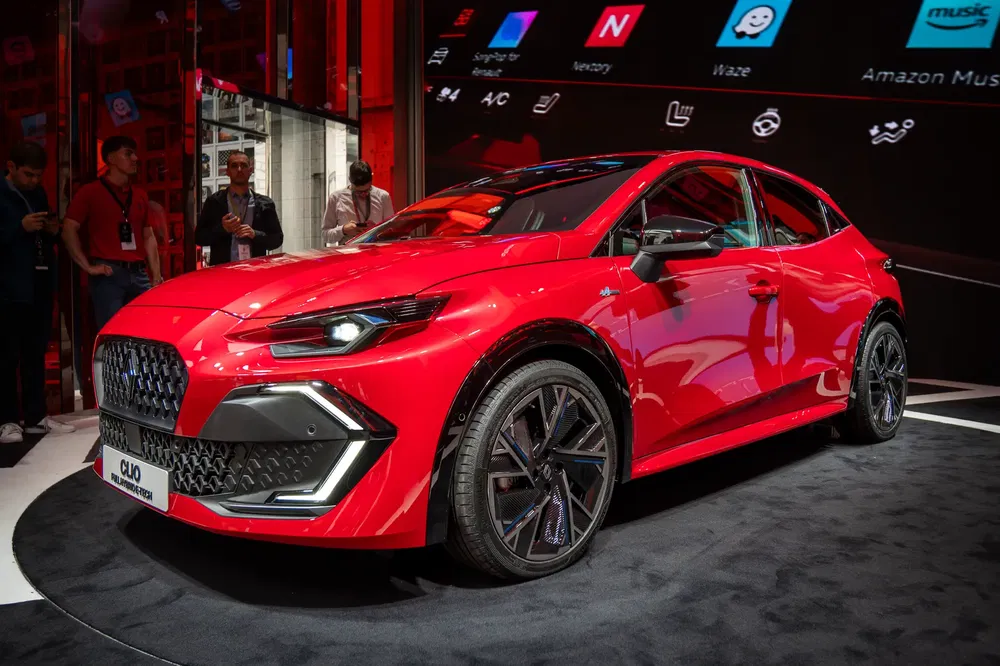 Rode Renault Clio gepresenteerd op een autoshow met moderne verlichting en ontwerp.