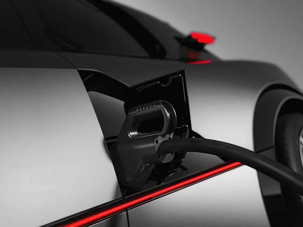 Voiture électrique chargeant, gros plan connecteur sur port de charge, lumière rouge accentuant.