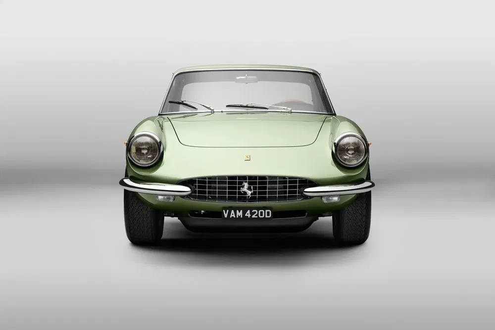 Ferrari 330 GT de 1965 en vert clair, vue avant, sur fond gris uni.