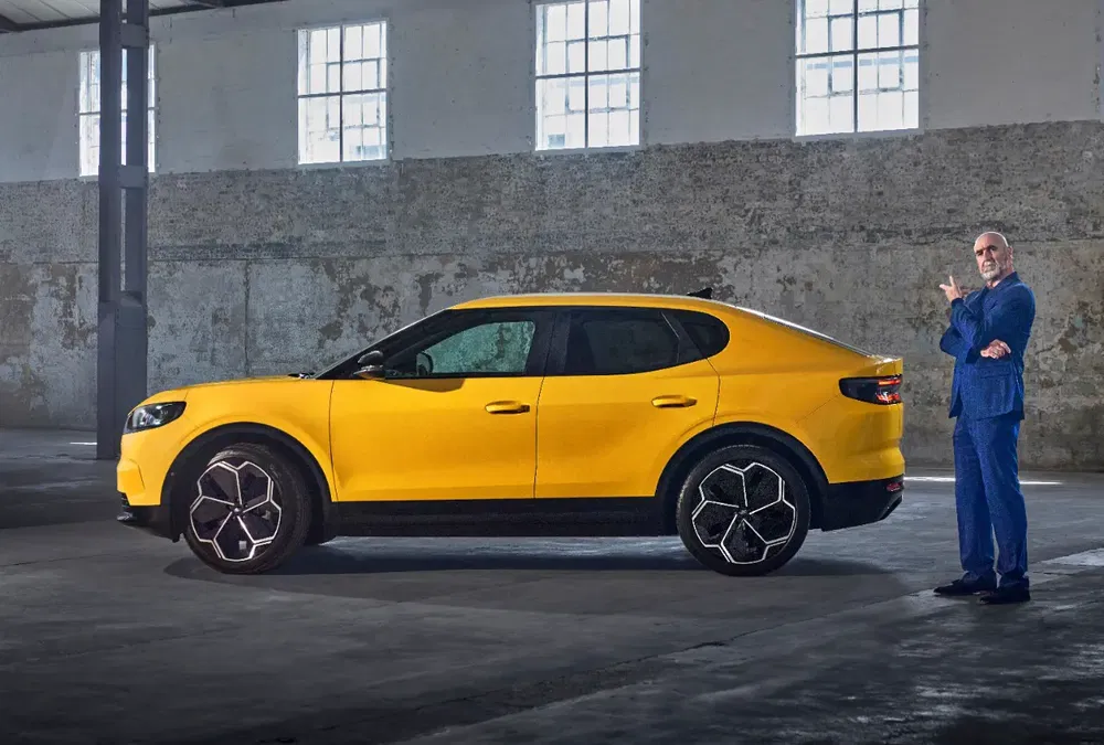 Voiture Lynk & Co jaune dans un entrepôt, homme en costume bleu en arrière-plan.