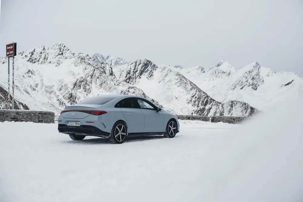 Mercedes-Benz EQE op besneeuwde weg met bergen op de achtergrond.
