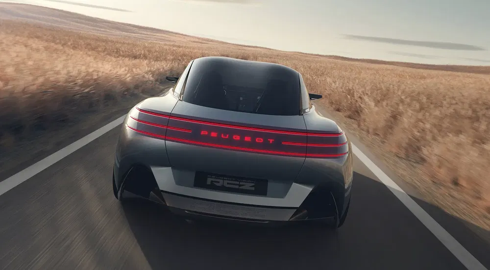 Concept-car Peugeot RCZ roulant sur une route de campagne, design futuriste et lignes fluides.