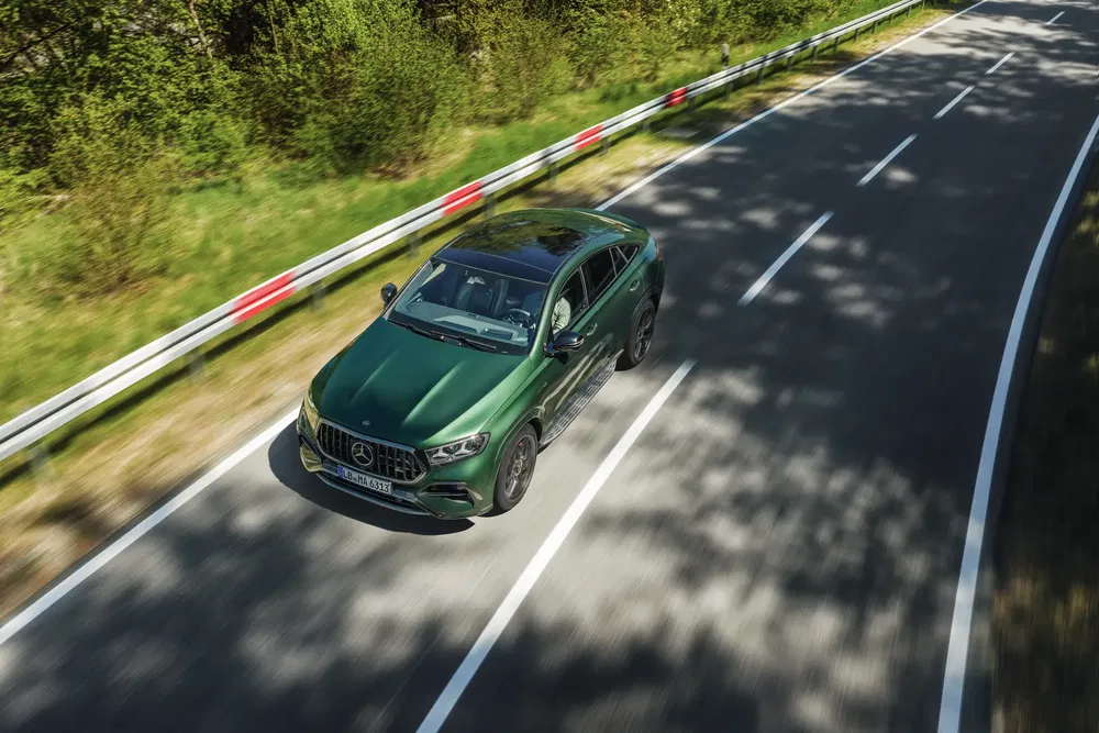 Mercedes-Benz GLE vert sur route forestière, captivant en mouvement dans un cadre naturel.