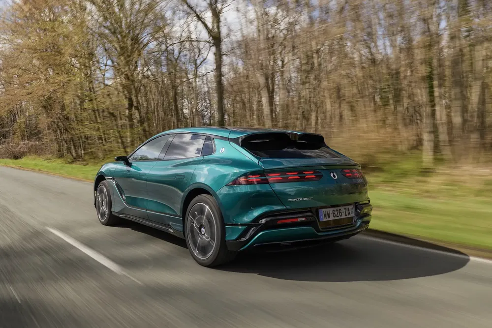 Voiture DS Aero Sport Lounge verte roulant sur une route bordée d'arbres.
